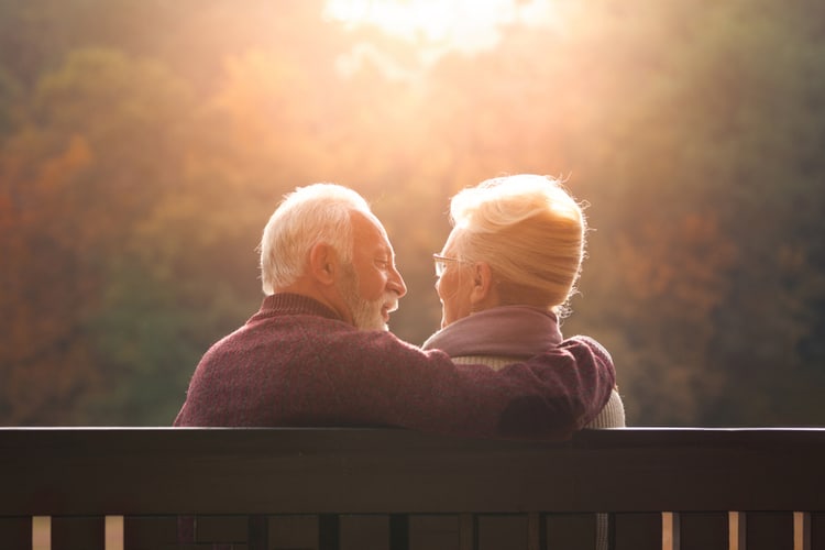 Senior couple sitting on a park bench in autumn