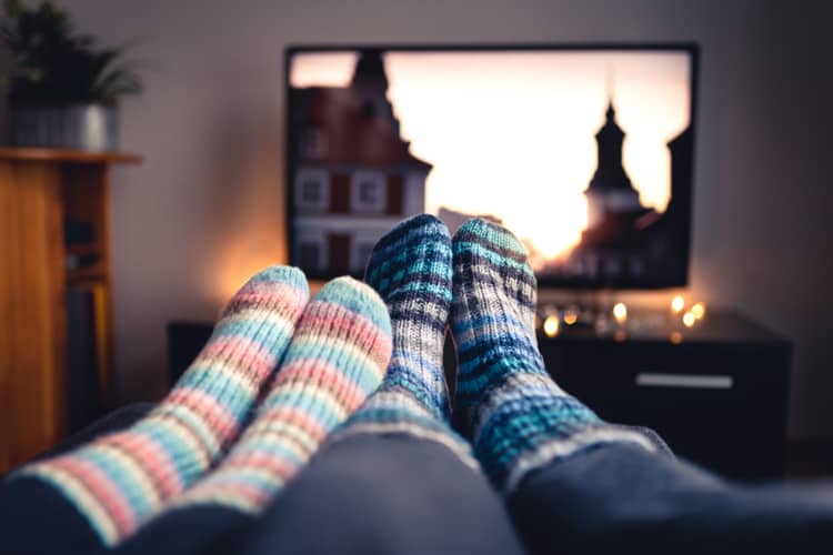 Two people sitting with their feet up while watching television