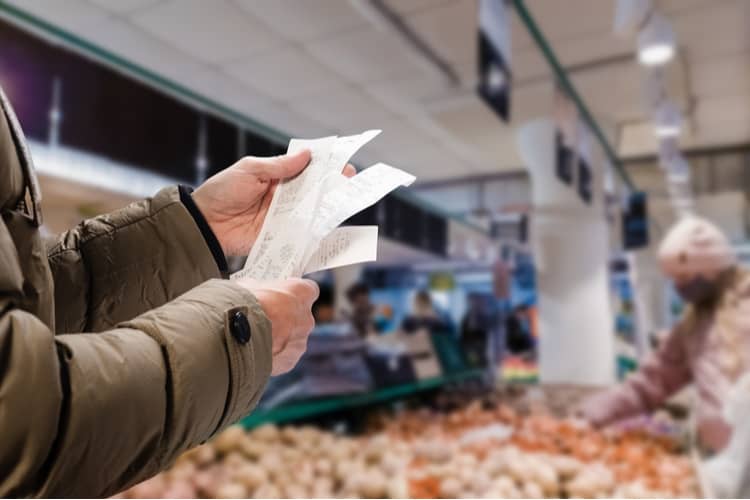 A person holding up a receipt in a supermarket.