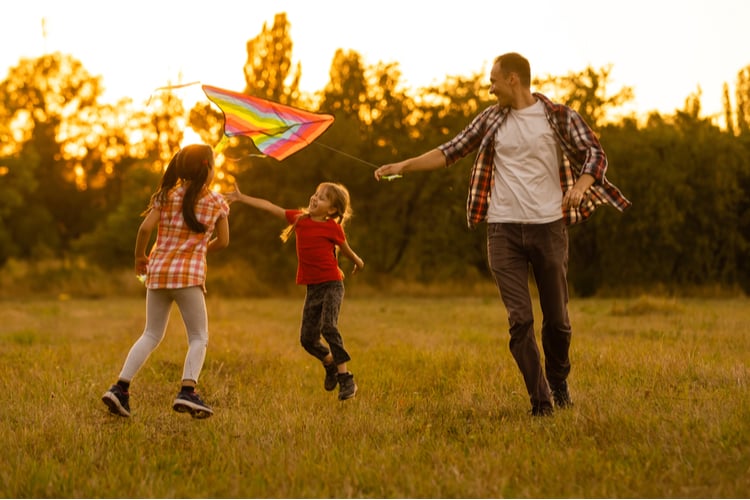A father and two children playing with a kite.
