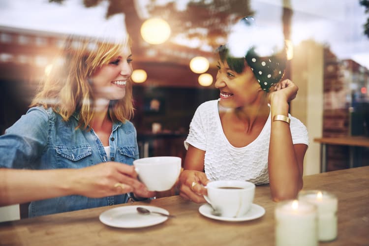 Two women talking while drinking coffee.