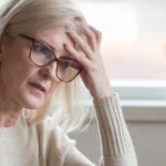 A retired woman looking worried while using a laptop.