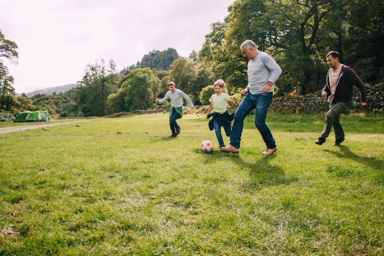 Multi-generational family playing football in a park.