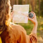 A young woman hiking and using a compass.