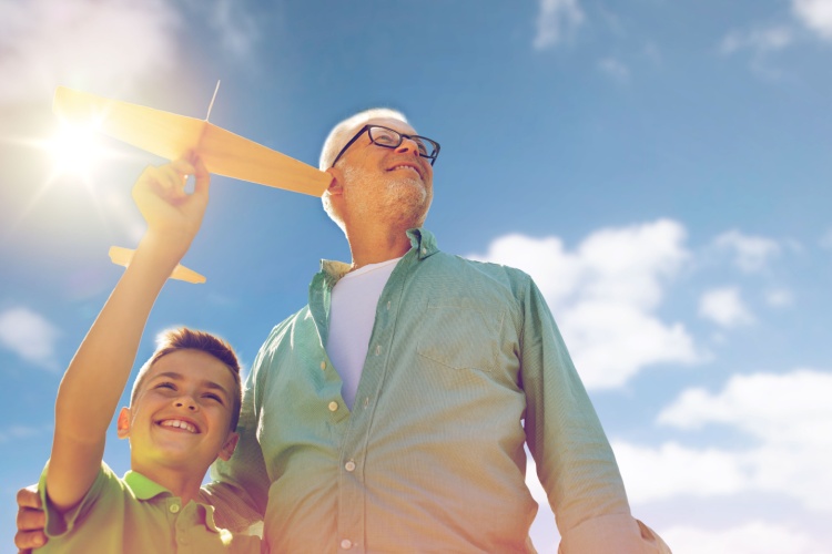 A grandfather and grandson playing with a toy plane outdoors.