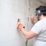 A tradesperson repairing a crack in a wall.