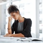 A woman pinching the bridge of her nose in an office.