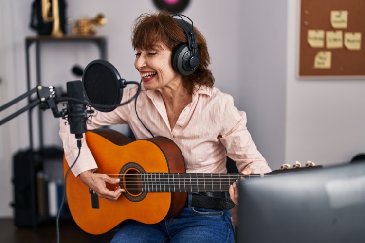 A woman playing a guitar in a music studio.