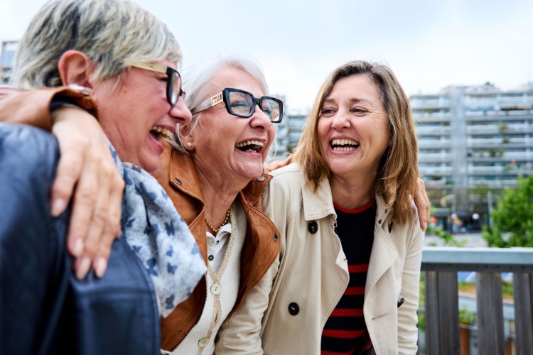 Three women with the around each other laughing.