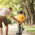 A father teaching a child to ride a bike.