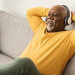 A man relaxing on a sofa with his hands behind his head.