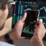 A man looking at a graph showing stock market performance on his phone.