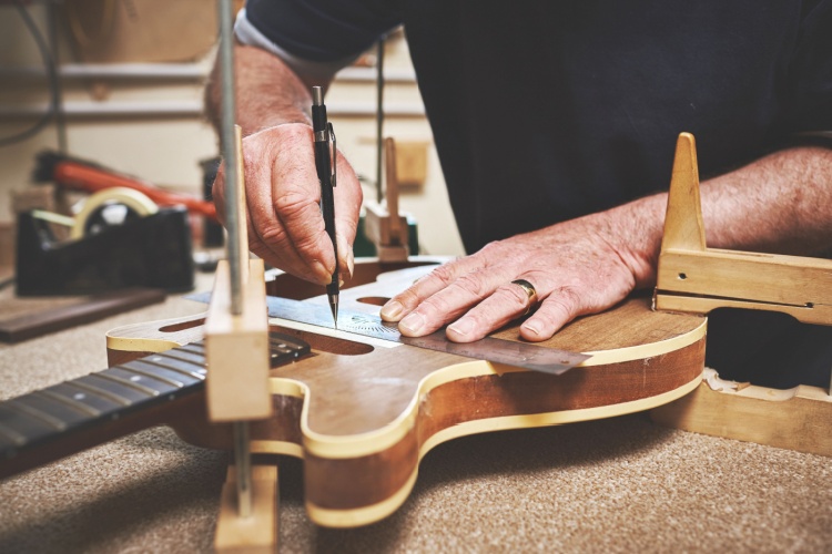 A man fixing a guitar in a workshop.