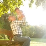 A grandfather playing with his young grandson in a park.
