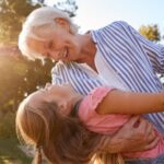 A grandmother playing with her granddaughter outside.