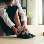 A girl putting on school shoes.