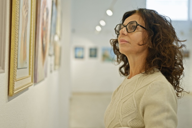 A woman looking at a painting in an art gallery.