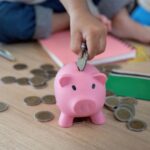 Child putting coins into a piggy bank