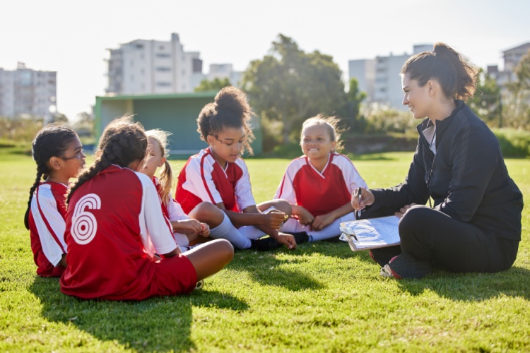A woman coaching a girl’s football team.
