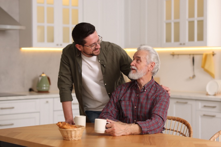 A father and son talking in a kitchen.
