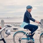 A woman cycling along a beachfront.