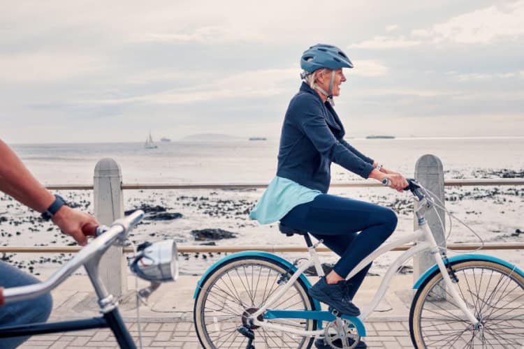 A woman cycling along a beachfront.