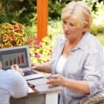 Female financial planner showing a senior woman charts on a laptop