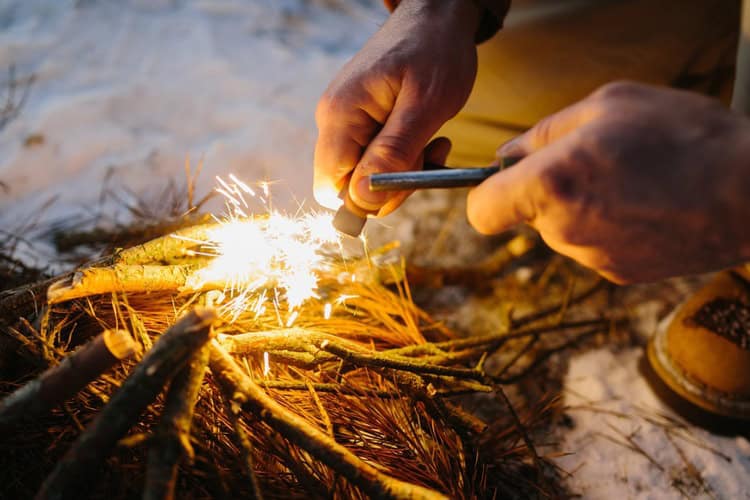 A close-up of a man starting a fire