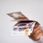A hand holding UK bank notes.