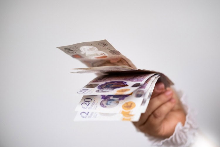 A hand holding UK bank notes.
