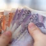 A person holding UK bank notes.