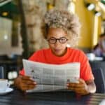 A woman reading a newspaper in a café.