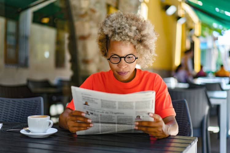 A woman reading a newspaper in a café.