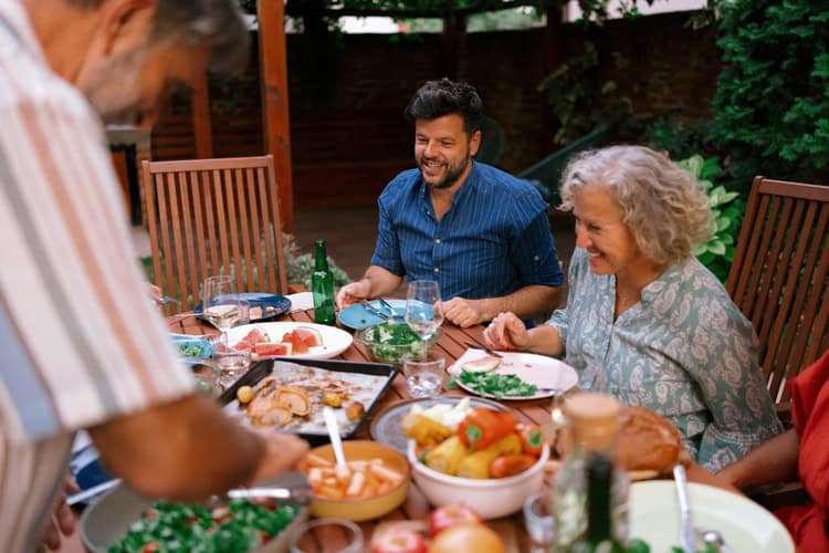 A multigenerational family eating together outdoors.