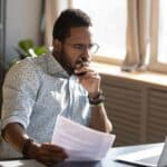 A man looking contemplatively at a desk.
