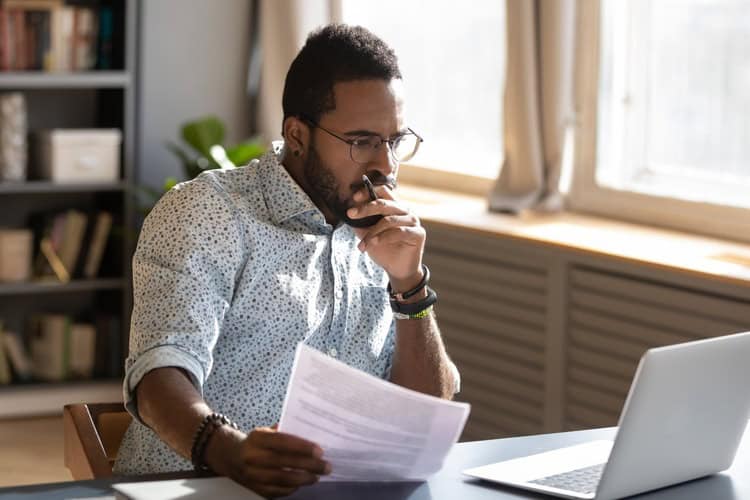 A man looking contemplatively at a desk.