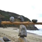Rocks balancing on log on top of another rock